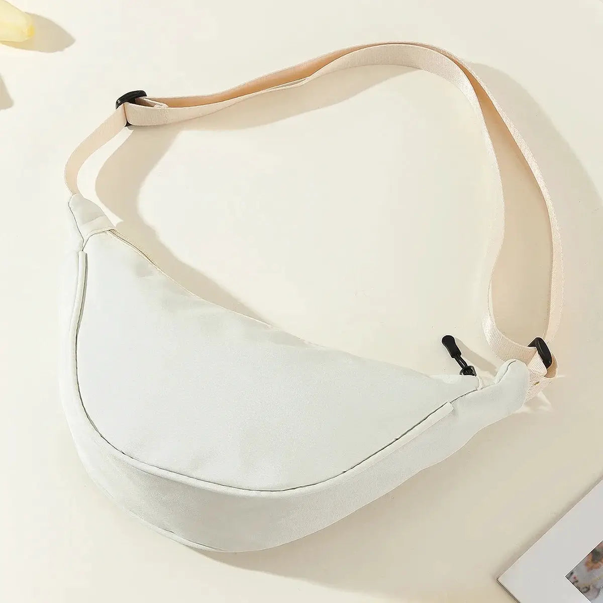 Nylon dumpling bag, small white crescent crossbody with pale pink adjustable strap.
