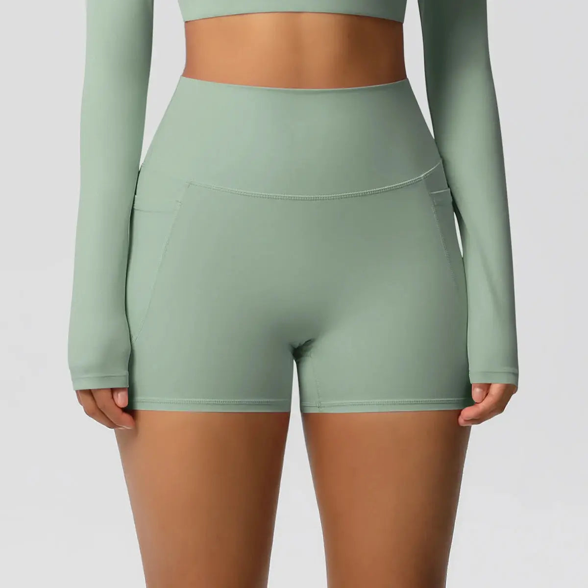 Women’s pocketed yoga shorts in sage green with high-waist, squat-proof, quick-dry fabric.