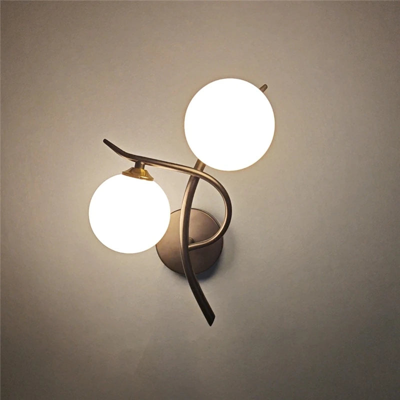Nordic modern iron wall lamp by Simples Market with two glass globes, LED, and curved bronze arms