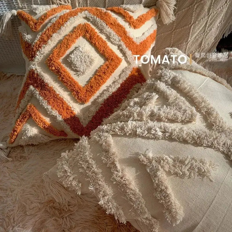 Bohemian pillow cover with geometric embroidery and orange tassel fringe on cream fabric for living room decor.