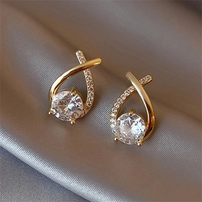 Pair of gold-tone cross-stud earrings with pavé crystal arc and a large central clear gemstone