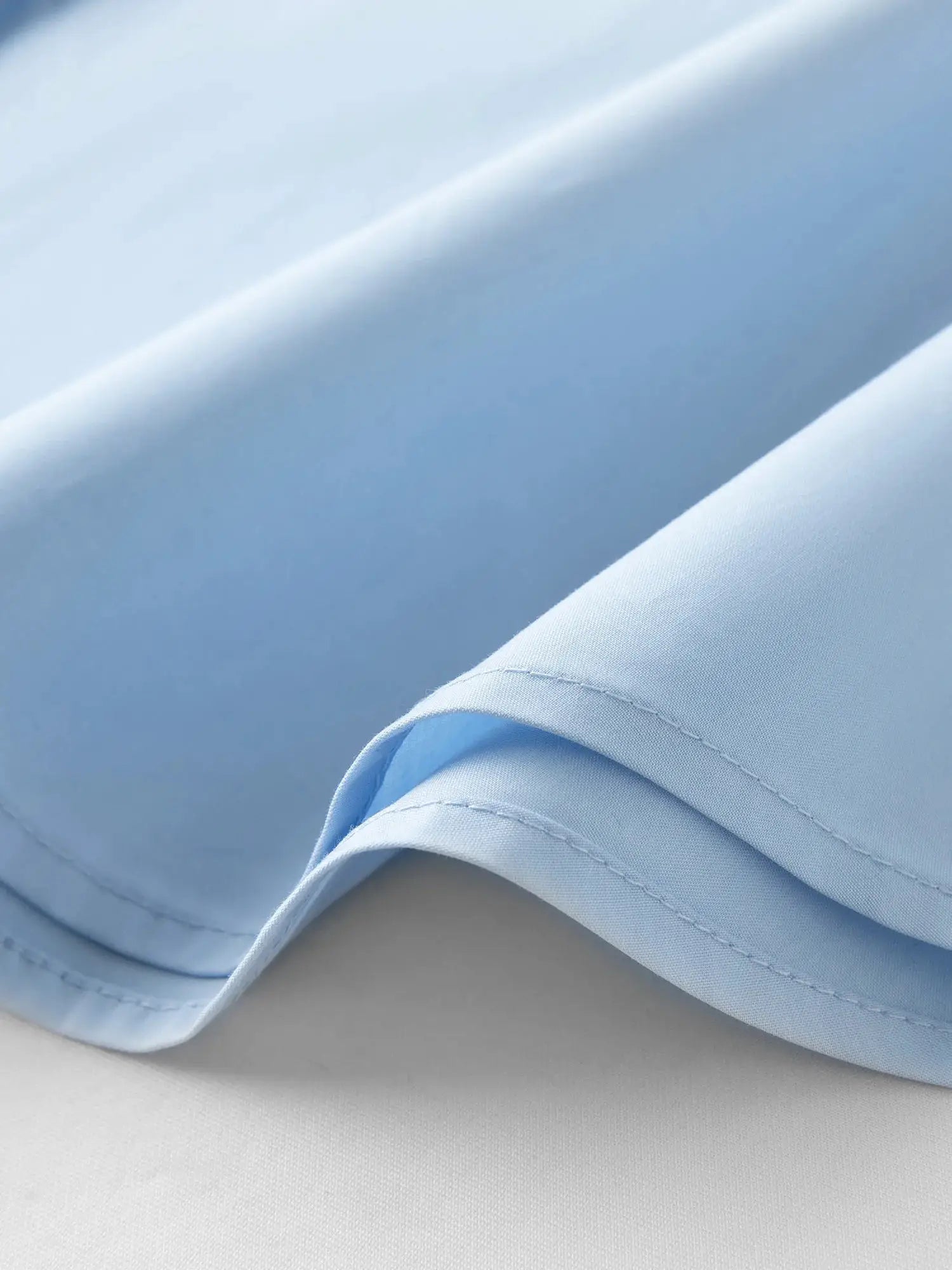 Cotton shirt sleeve cuff in blue, close-up with visible stitching.