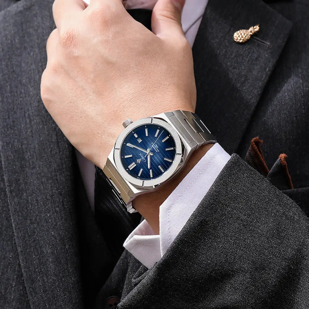 CADISEN diver watch with blue dial and stainless steel bracelet worn on a gentleman's wrist.