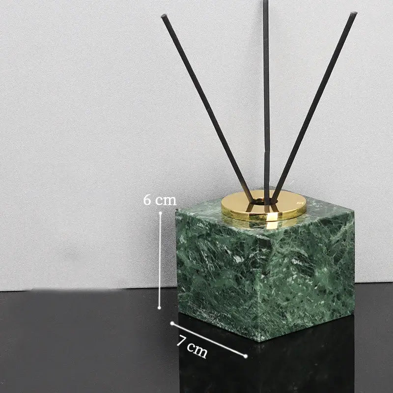 Green marble bathroom diffuser with black reed sticks and a gold cap