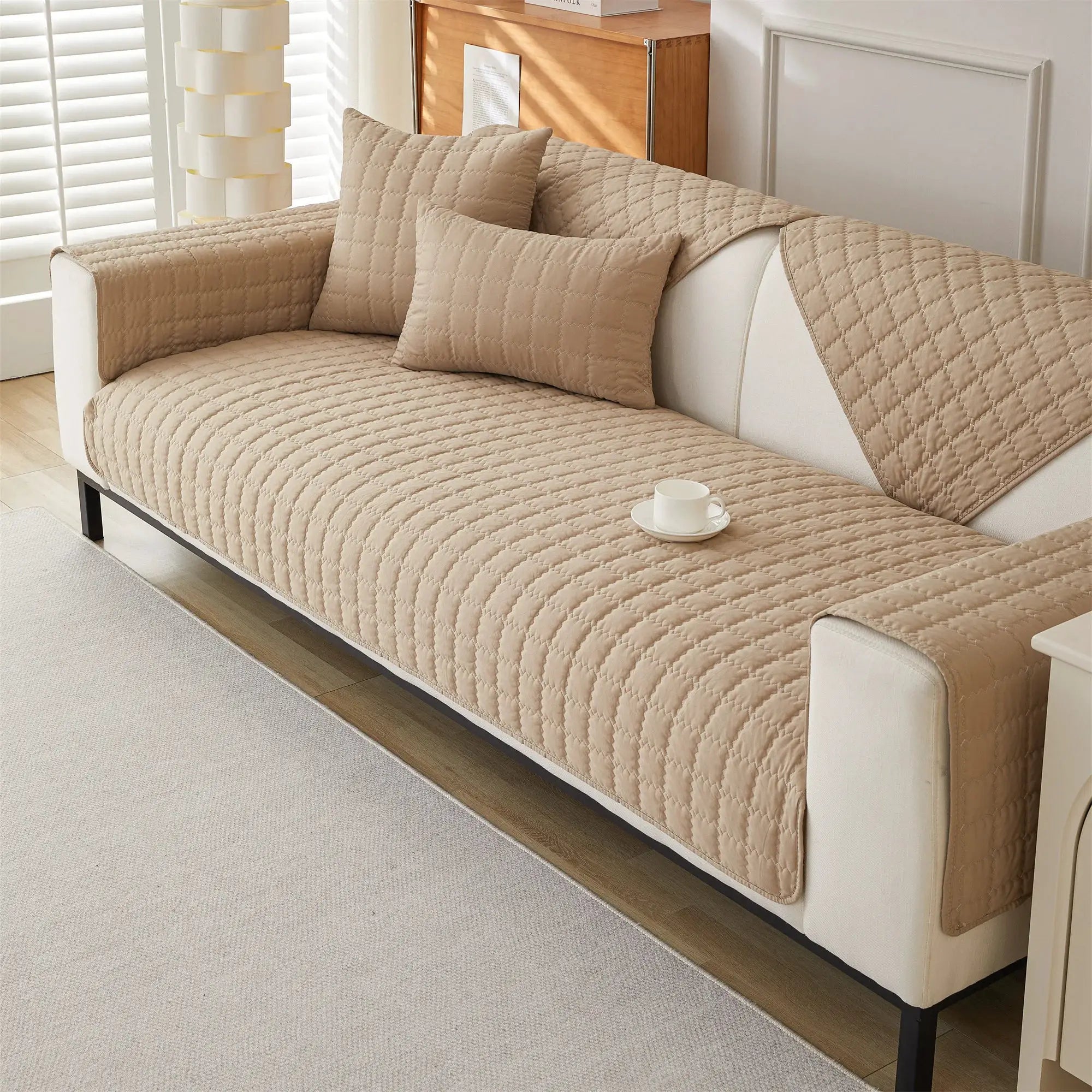 Sofa cover beige quilted anti-slip with two matching cushions on a living room sofa
