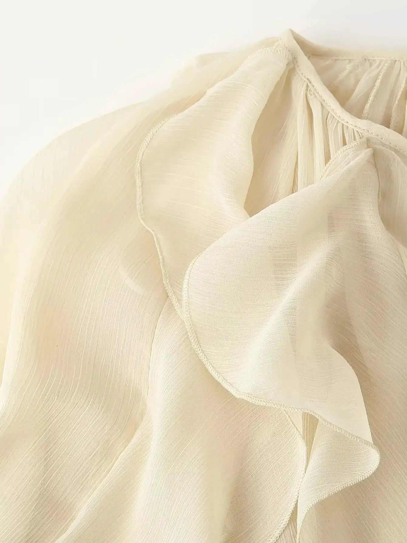 Cream semi-sheer blouse with cascading ruffles and long sleeves; delicate edge trim
