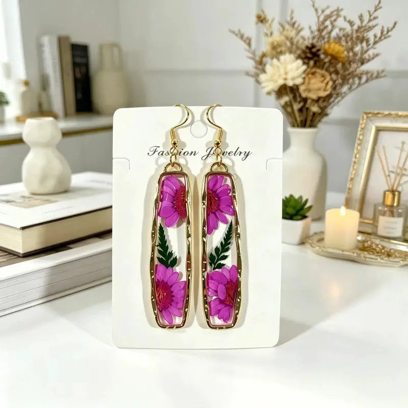 A pair of geometric pressed flower epoxy resin earrings in gold-tone rectangular frames with pink blossoms