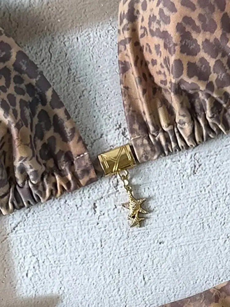 Leopard print bikini top with gold clasp and star charm, part of a two-piece swimsuit.