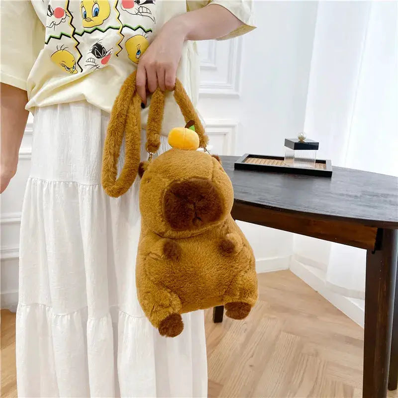 Cute plush capybara backpack in brown fur with orange fruit accent, crossbody bag