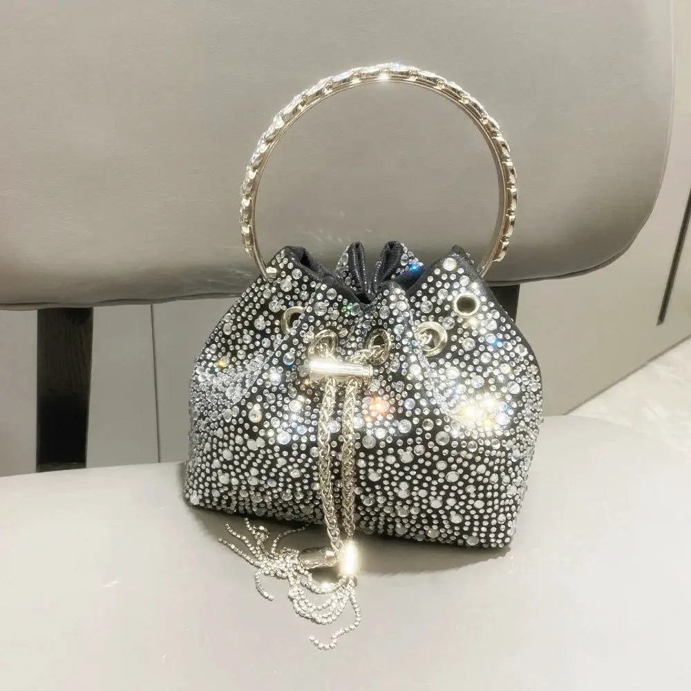 Simples Market rhinestone evening clutch bag with circular jeweled handle; silver crystal-dotted bucket purse.
