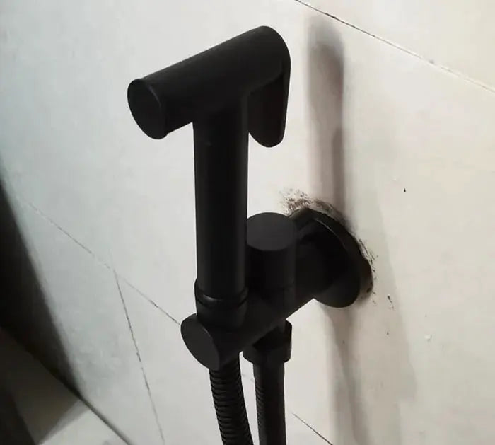 Black handheld bidet shower set with wall-mounted holder and flexible hose