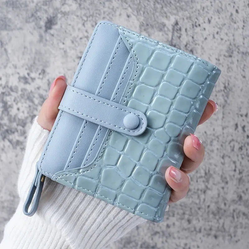 Mini crocodile-print clutch wallet in light blue faux leather with a strap closure