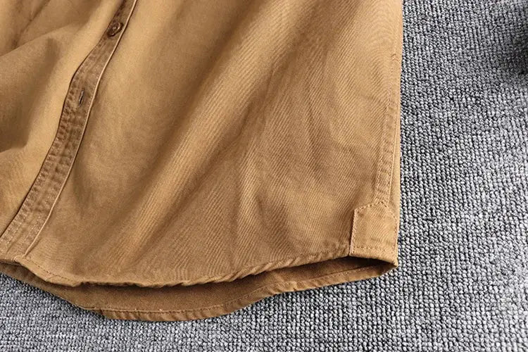 Simples Market men's khaki work shirt with solid color fabric and curved hem detail.