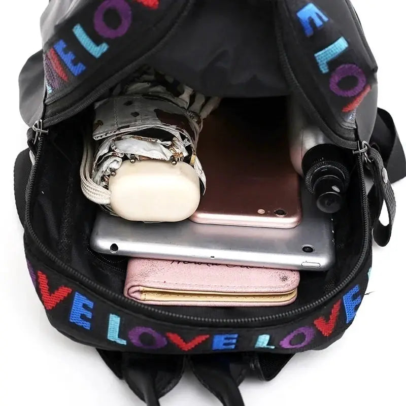 Women black LOVE backpack open to reveal phone, tablet and wallet inside.