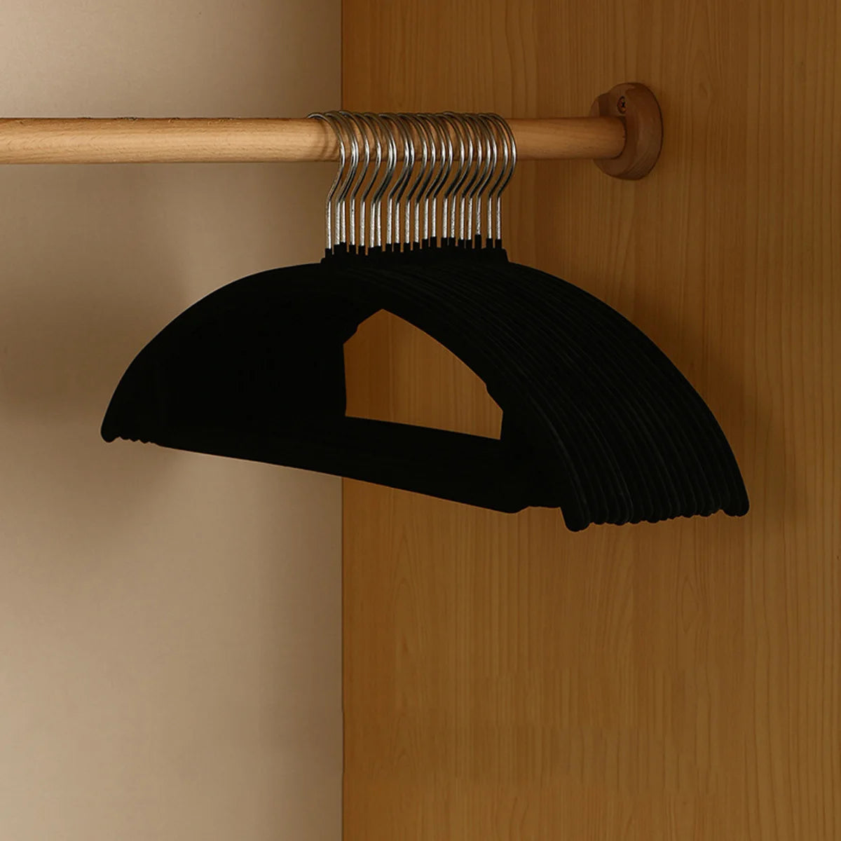 Black velvet hangers set on a wooden closet rod; slim, non-slip, space-saving.