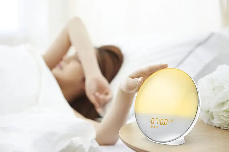 Sunrise Alarm Clock Wake Up Light Clock, a round bedside digital clock with orange sunrise glow on a nightstand