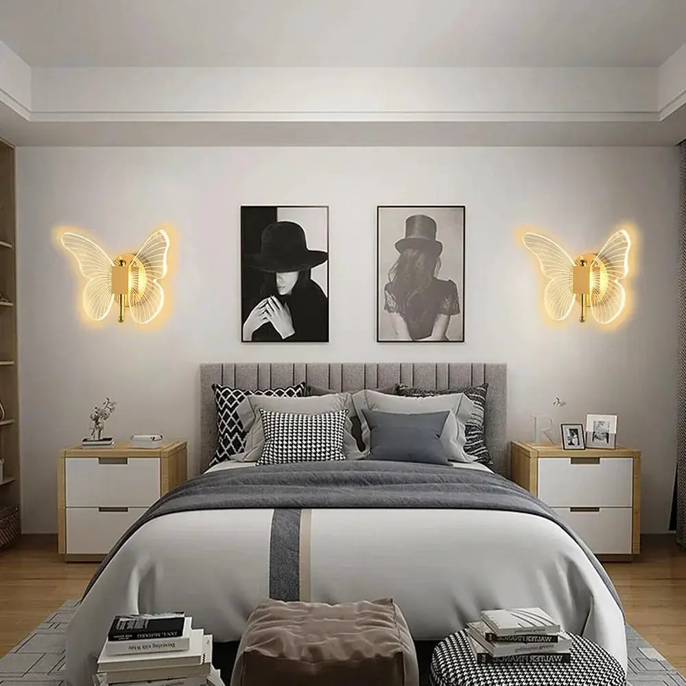 Butterfly LED wall lamp pair in metal with acrylic wings, warm yellow glow at bedside.