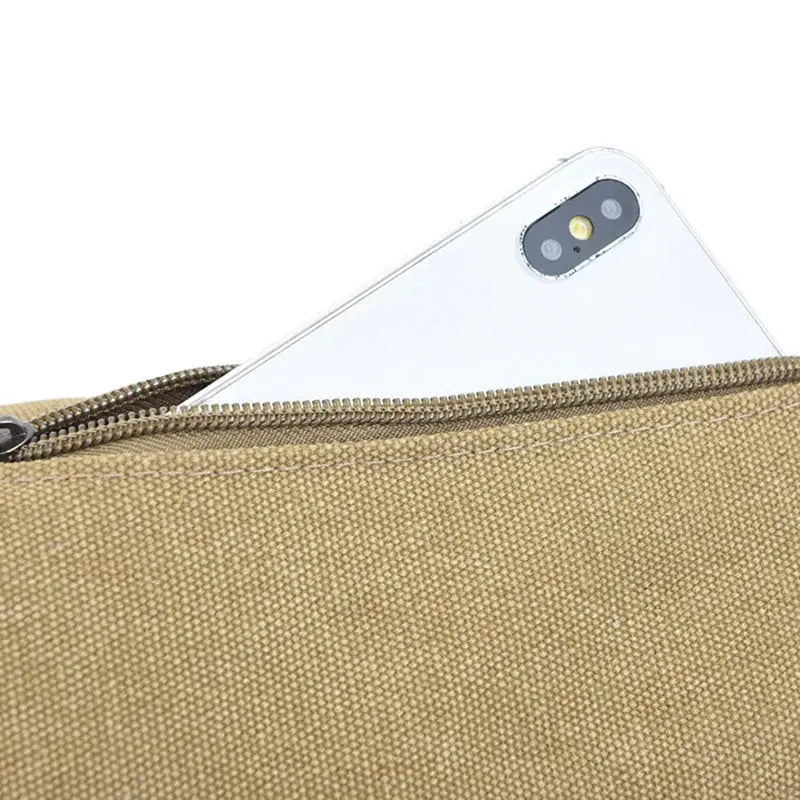 Tan canvas chest/waist bag with a zipper pocket and a smartphone partially inserted