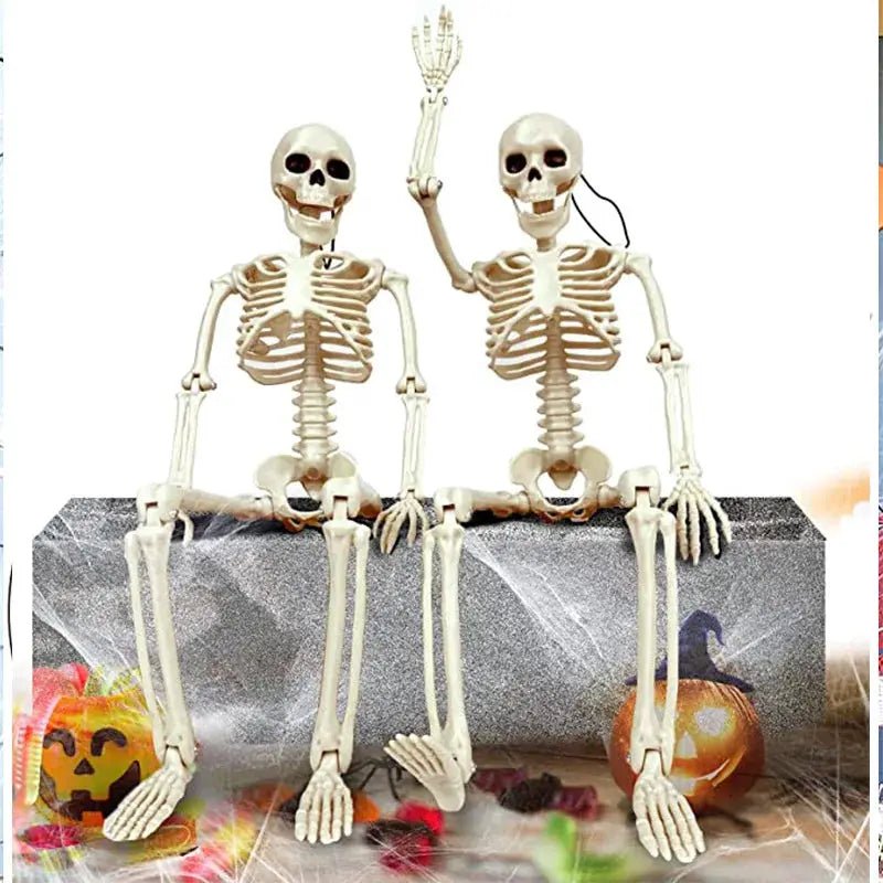 Two plastic Halloween skeleton figurines with beige bones, seated on a gray block with pumpkins.