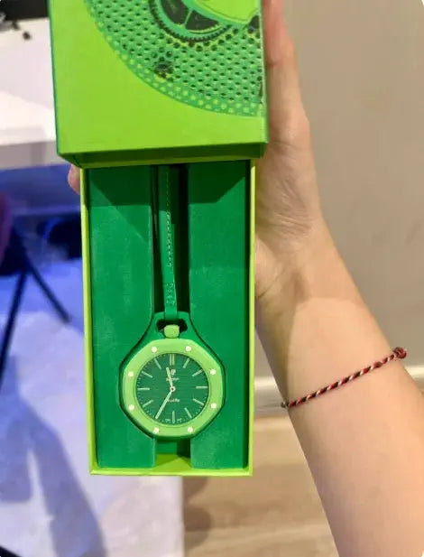 Green wristwatch with green dial and strap in a bright green presentation box.