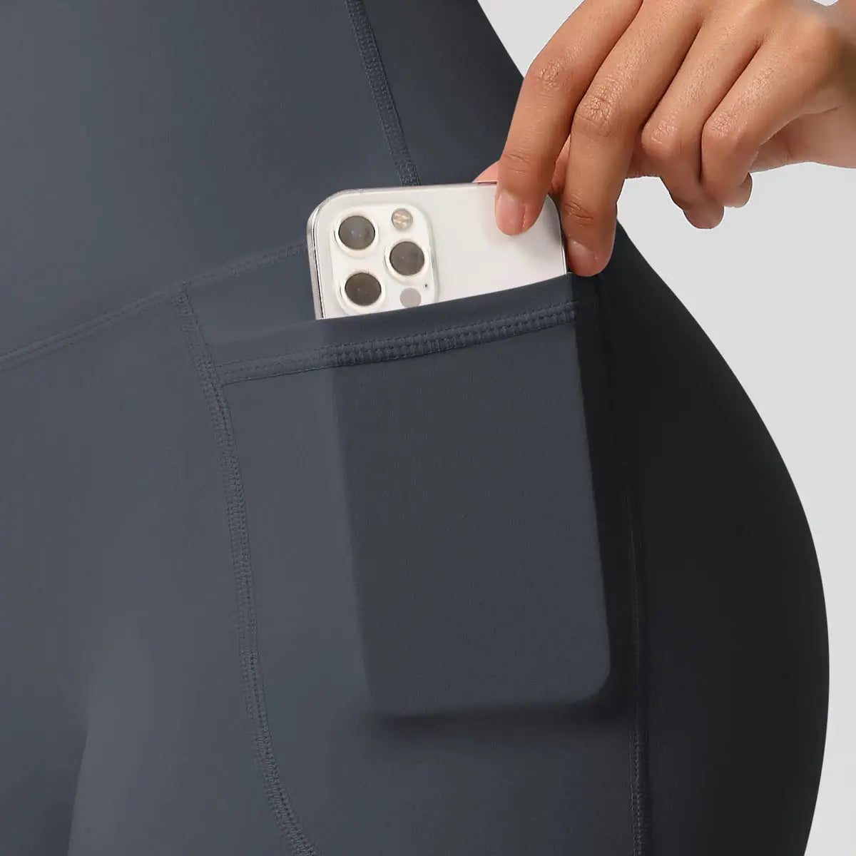Women pocketed yoga legging shorts in dark gray with high waist; phone tucked in pocket.