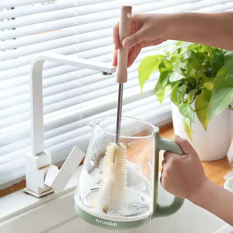 Wooden bottle cleaning brush with long handle cleaning a Hyundai glass pitcher with a green base