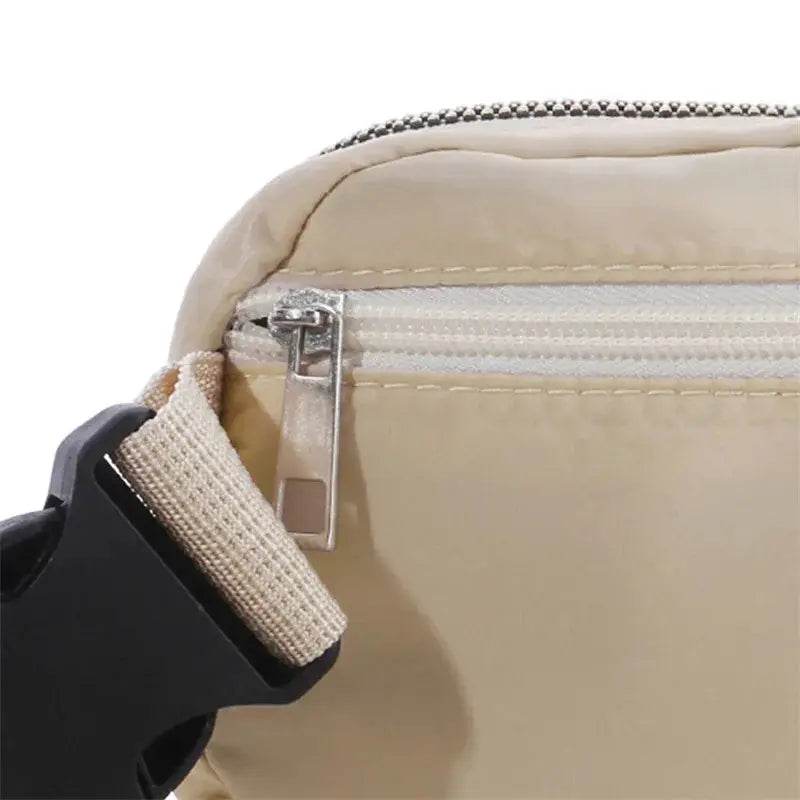 Beige women's waist bag with zipper closure and adjustable strap.