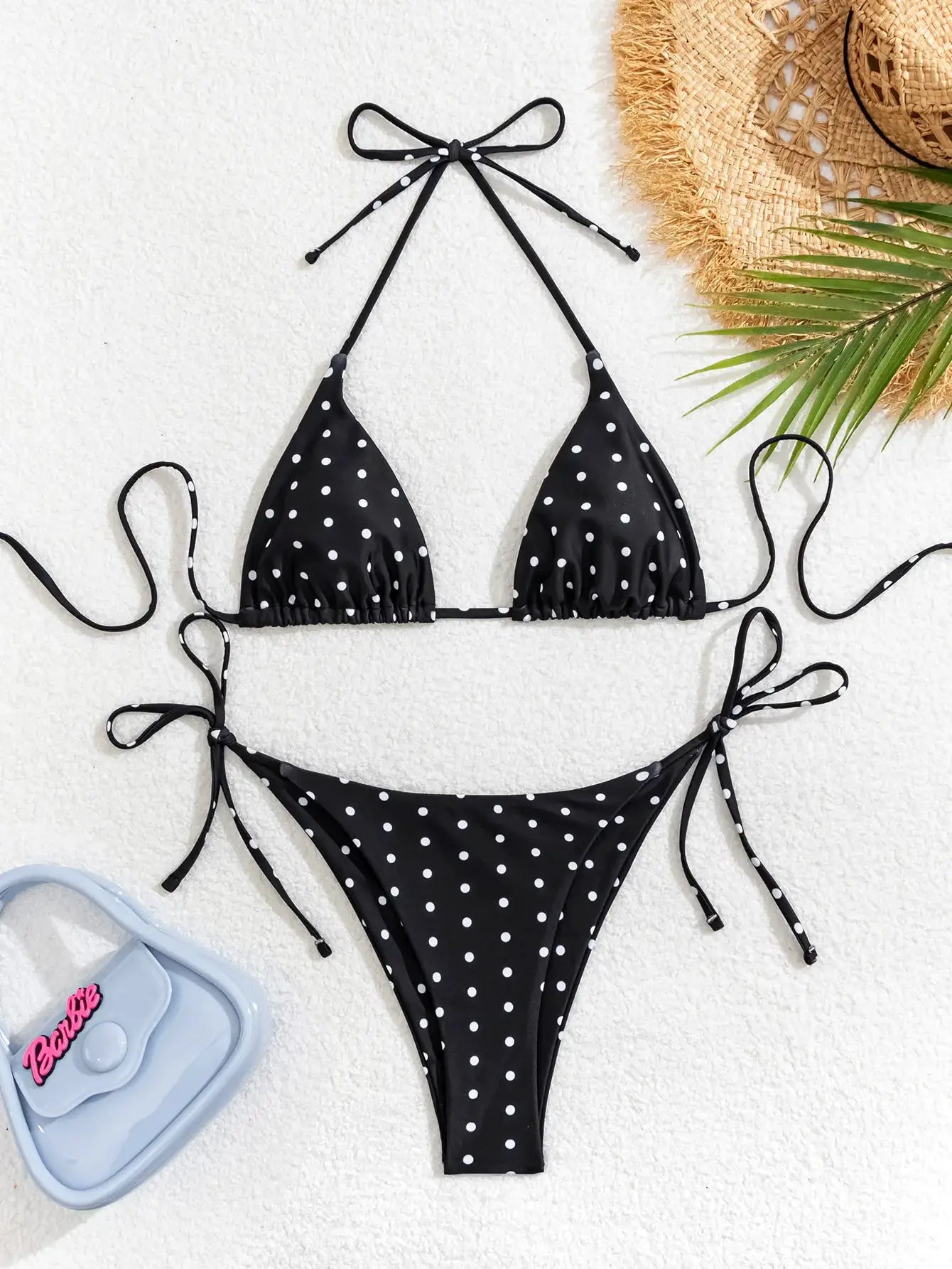 Black polka dot bikini set with triangle top and tie-side bottoms, adjustable straps; Barbie bag pictured.