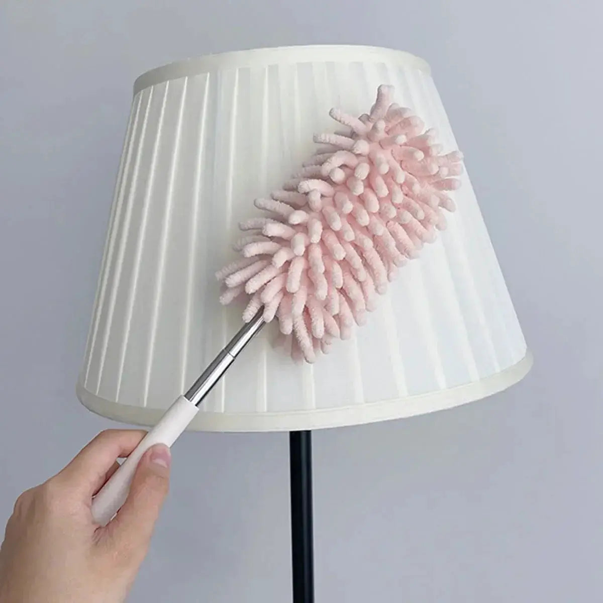 Mini car duster brush with extendable bendable pink microfiber head cleaning a white lampshade