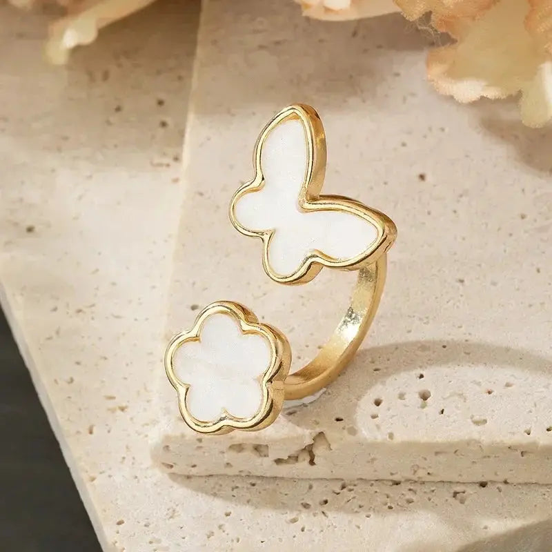 Adjustable ring with gold-tone finish featuring white enamel butterfly and flower accents
