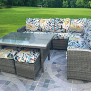 Outdoor tropical print sofa cushions on a woven wicker sectional with a glass coffee table