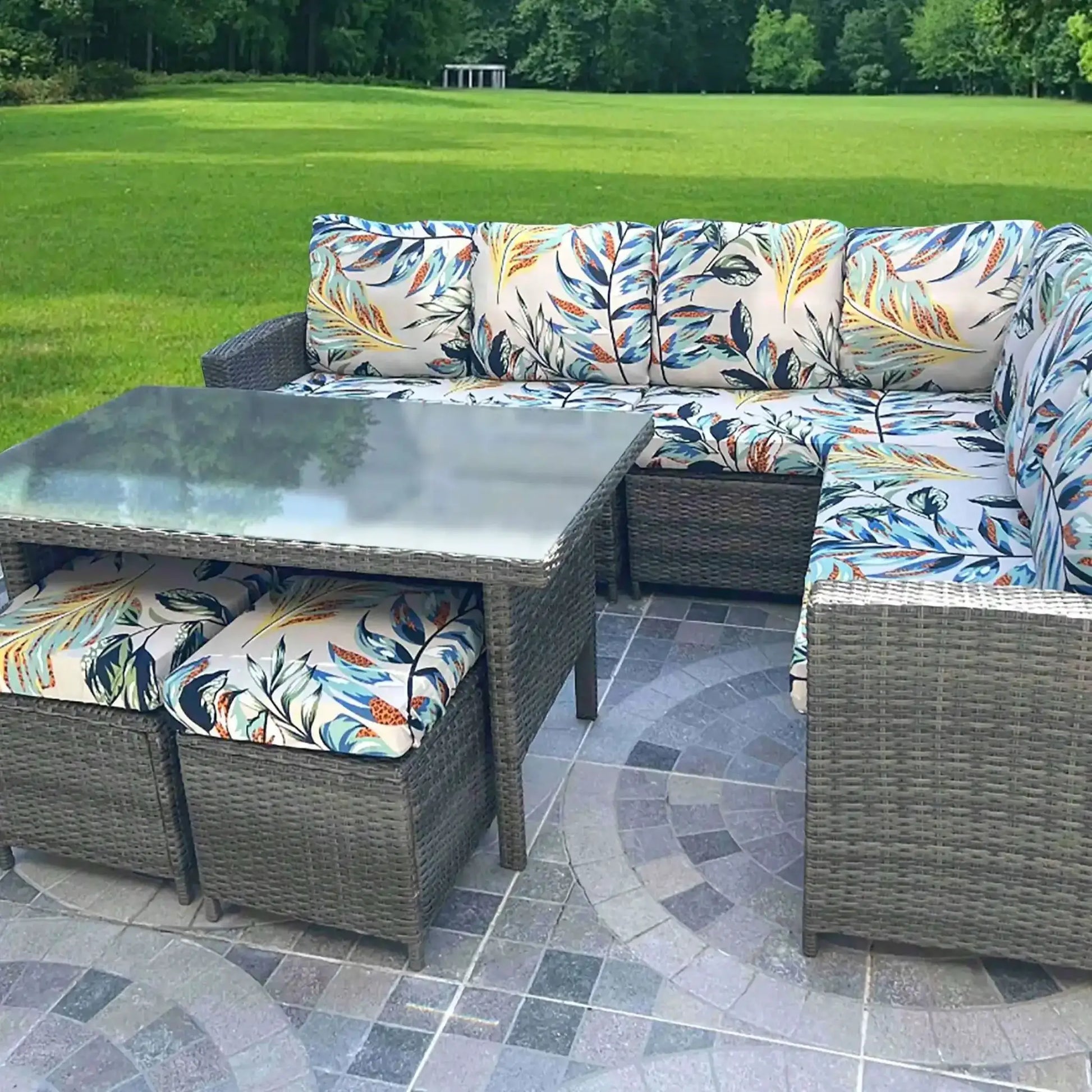 Outdoor tropical print sofa cushions on a woven wicker sectional with a glass coffee table