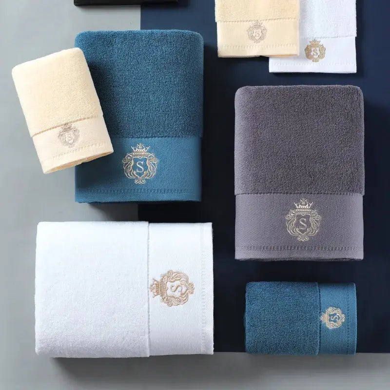 Cotton towel set by Simples Market with embroidered crest logos on white, blue and gray towels