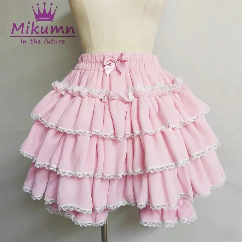 Pink layered Lolita skirt with white lace trim and waist bow; Mikumm logo visible.