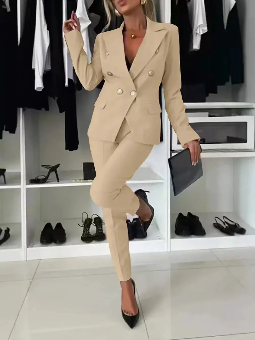 Beige two-piece women's office suit with a double-breasted blazer and matching trousers, paired with black heels
