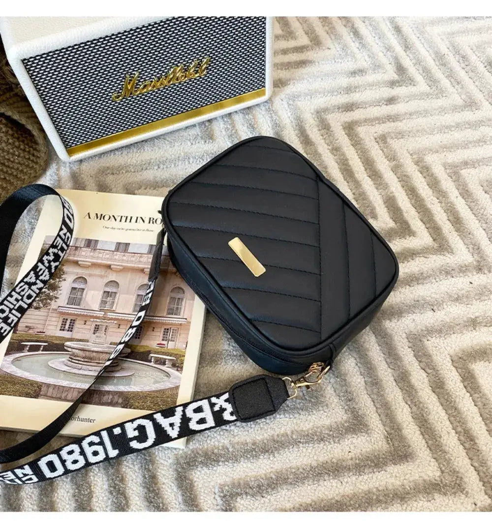 Black PU leather shoulder bag with diagonal quilted stitching and gold-tone hardware, crossbody strap.