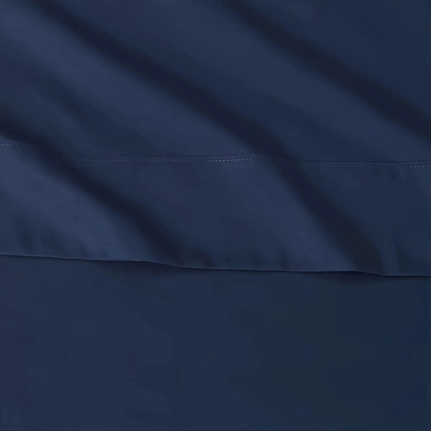 Sheet set in navy blue with visible white stitching along seam