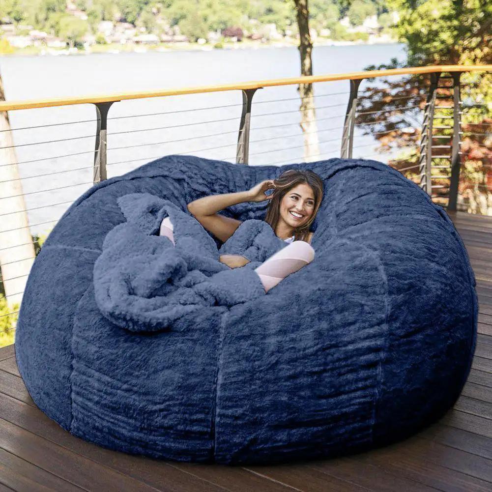 Blue plush bean bag sofa bed on an outdoor wooden deck with a smiling woman lounging inside