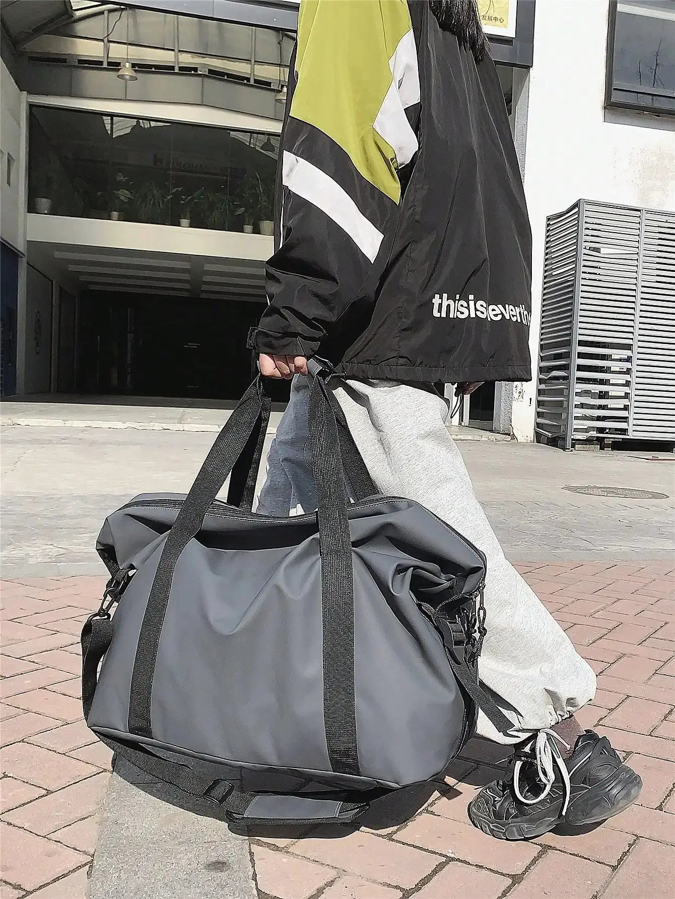 Grey large-capacity handheld travel duffel bag with black shoulder strap and top handles.