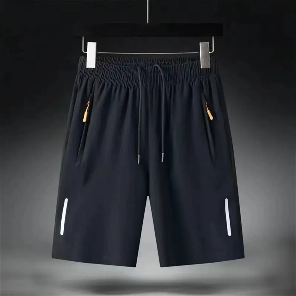 Men's black quick-dry shorts with elastic waistband, orange zipper pulls on pockets, and reflective leg accents.