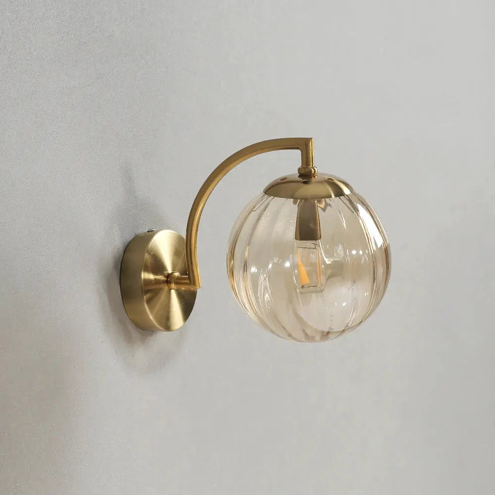 Modern LED wall lamp with brass finish and clear glass globe, bedside sconce.
