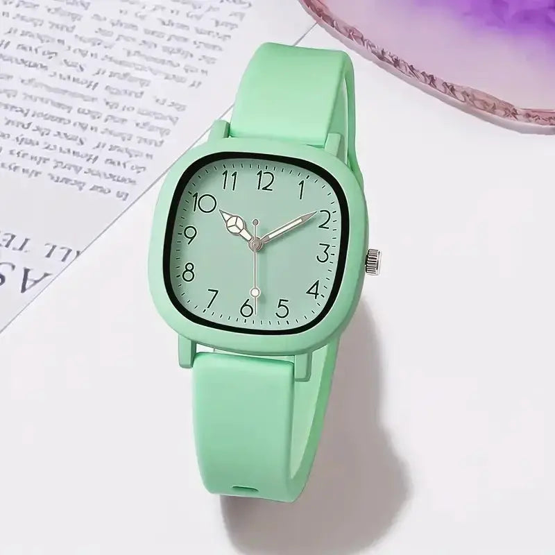 Watch with mint green silicone band, rounded-square dial, and Arabic numerals.