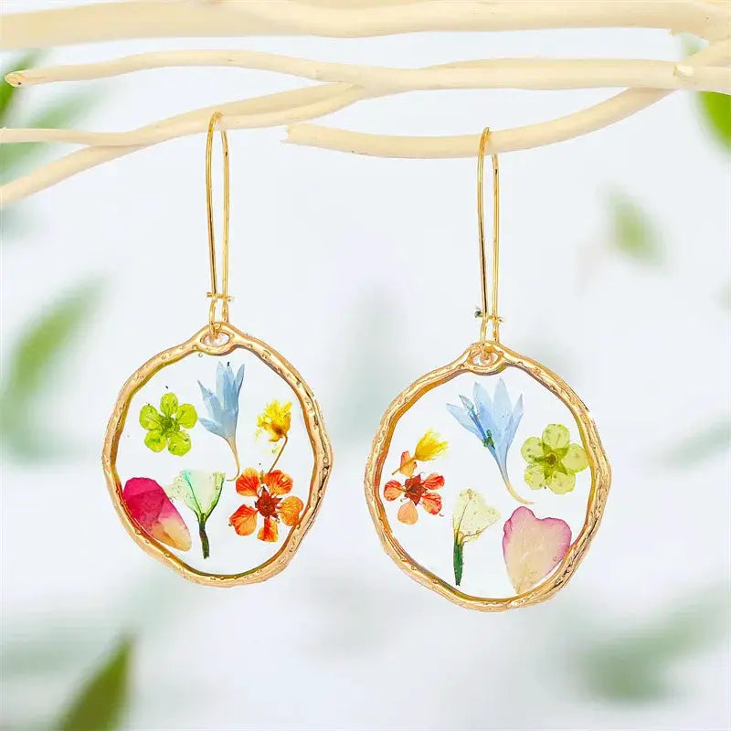 Natural flower dangle earrings pair by Simples Market; gold-tone hoops with colorful pressed flowers in epoxy resin