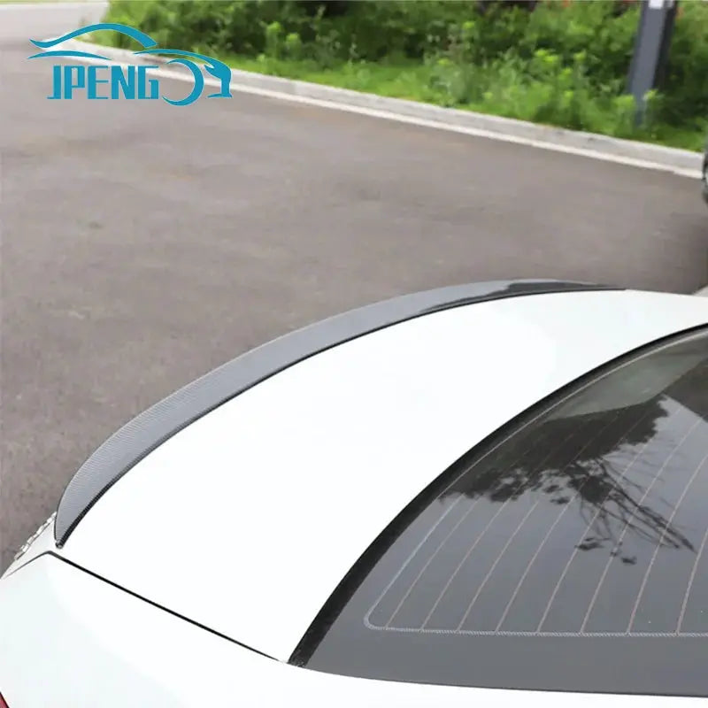 Universal spoiler lip rear wing on white sedan, gray carbon-fiber finish across trunk, JPENG logo visible