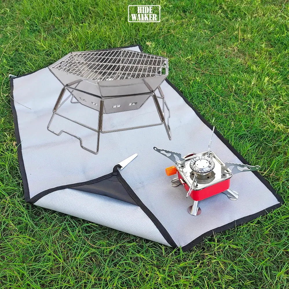 Camping fireproof cloth BBQ grill mat by Simples Market, gray with black edge on grass beneath a portable stove.