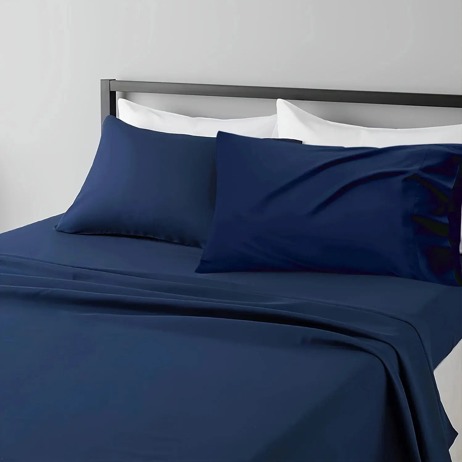 Navy blue breathable cooling sheet set on bed with white pillows