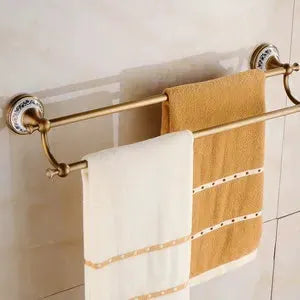 Towel bar set in antique brushed solid brass with two towels, white and tan, on ceramic hardware.