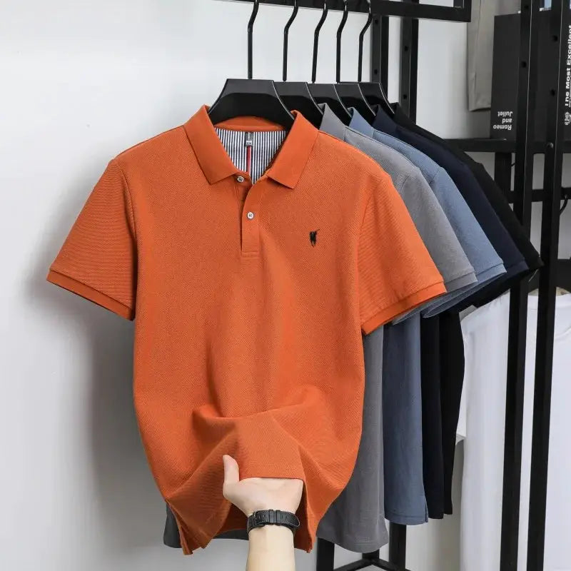 6 polo shirts on rack; orange short-sleeve cotton polo in front with black pony embroidery
