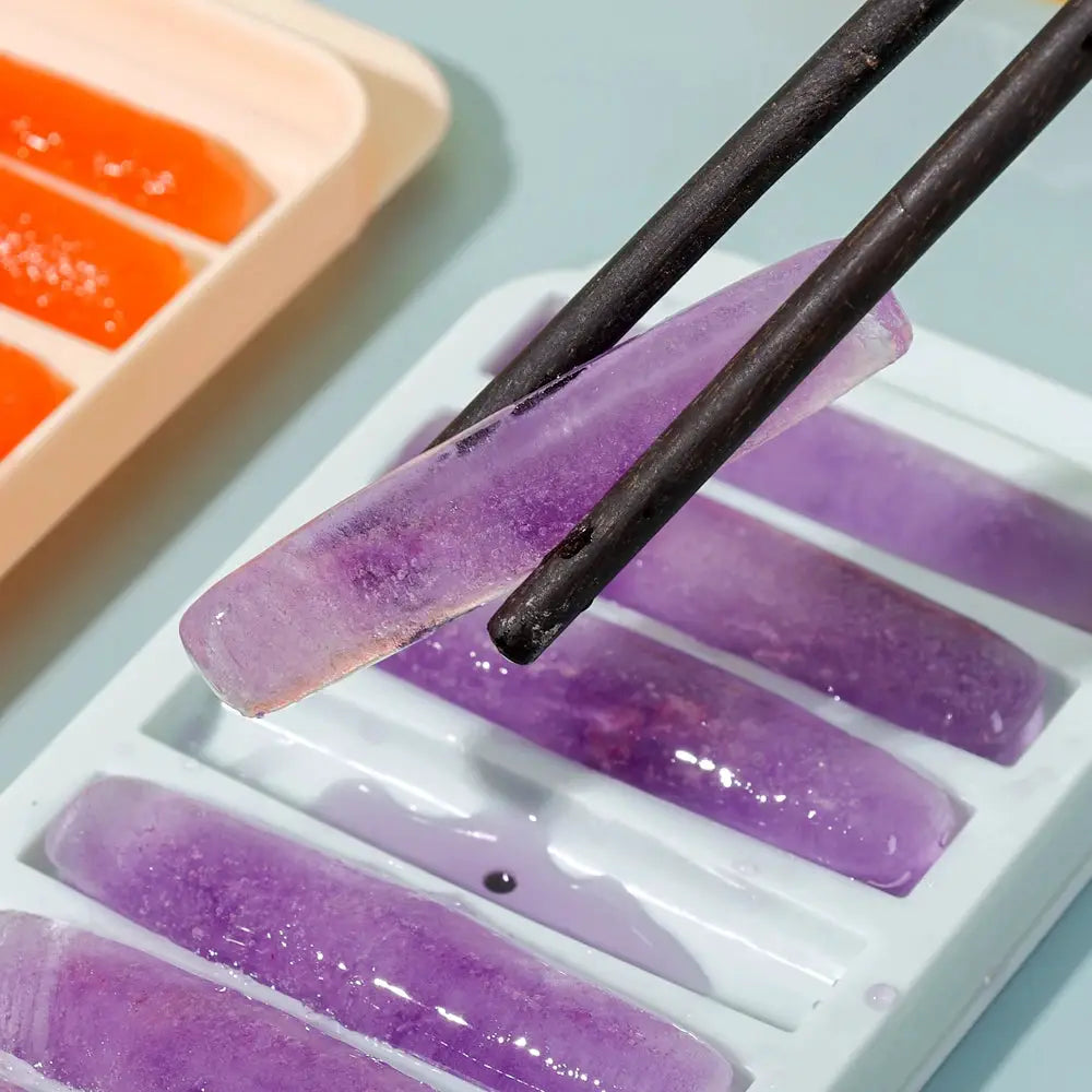 Long-bar cylindrical ice cubes mold; purple ice bars in a white tray, with chopsticks lifting one.