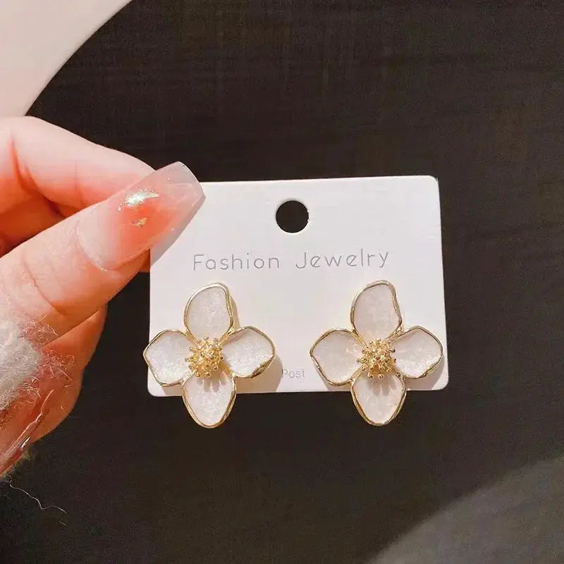 Enamel flower earrings, white petals with gold trim and yellow centers, pair on fashion jewelry card